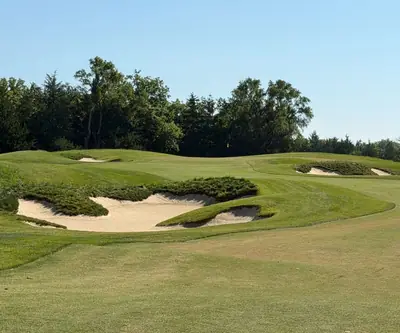 Deep bunkers guarding the approach to a green with a yellow flag at Quarry Oaks Golf Club in Ashland, Nebraska