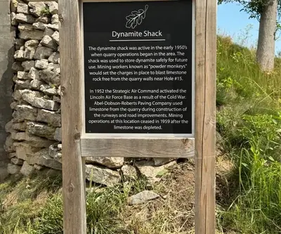 Historical marker for the 1950s dynamite shack beside a limestone wall at Quarry Oaks Golf Club in Ashland, Nebraska