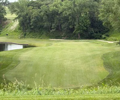 Elevated view of a fairway beside a pond below a wooded hillside at Quarry Oaks Golf Club in Ashland, Nebraska