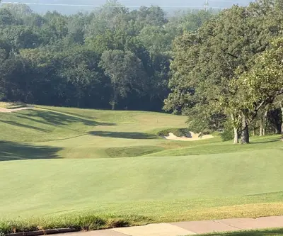 Elevated view down a fairway to a bunkered green framed by oaks at Quarry Oaks Golf Club in Ashland, Nebraska