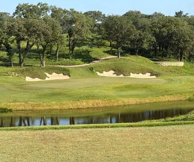 Pond in front of a green framed by sand bunkers and oak trees at Quarry Oaks Golf Club in Ashland, Nebraska