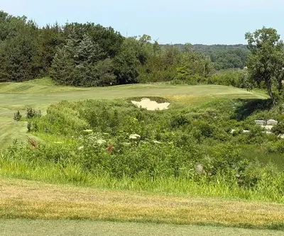 Green with a front bunker beyond a wildflower-filled ravine at Quarry Oaks Golf Club in Ashland, Nebraska