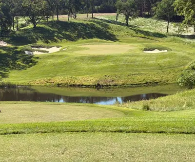 Tee view across a pond to a green guarded by bunkers at Quarry Oaks Golf Club in Ashland, Nebraska