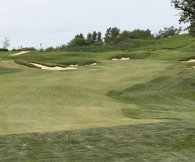 Rolling fairway leading to a bunker-guarded green below a grassy hillside at Quarry Oaks Golf Club in Ashland, Nebraska
