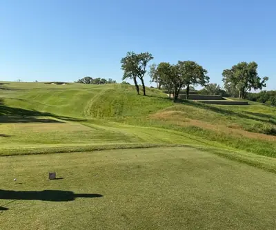 Tee box view of a rolling uphill fairway and stone retaining walls at Quarry Oaks Golf Club in Ashland, Nebraska