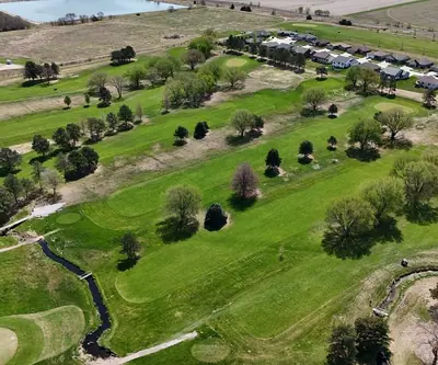 Aerial view of fairways, a winding creek and neighboring homes at Poco Creek Golf Course in Aurora, Nebraska