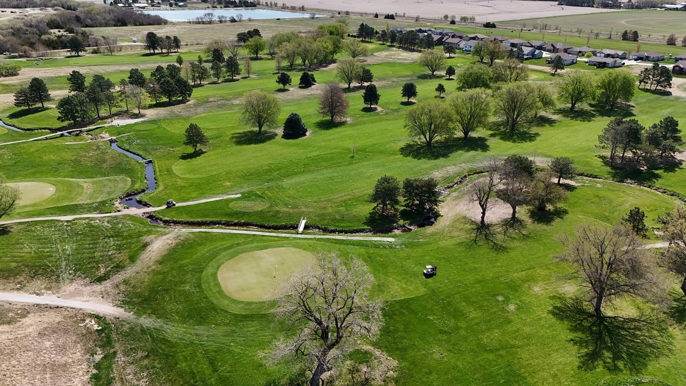 Aerial view of a green, winding creek, cart paths and tree-lined fairways at Poco Creek Golf Course in Aurora, Nebraska
