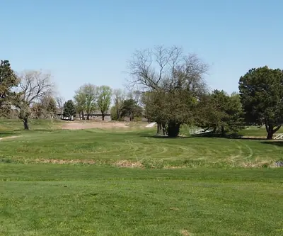Fairway crossing a grassy creek with white footbridges and mature trees at Poco Creek Golf Course in Aurora, Nebraska