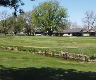 Creek running in front of a green lined by homes and trees at Poco Creek Golf Course in Aurora, Nebraska