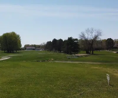 Open fairway with a small footbridge over a creek and homes beyond at Poco Creek Golf Course in Aurora, Nebraska