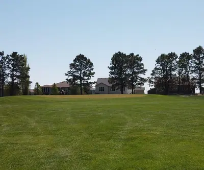 Wide open fairway lined with pine trees and homes at Poco Creek Golf Course in Aurora, Nebraska