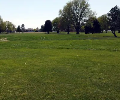 Wide open fairway lined with mature trees and nearby homes at Poco Creek Golf Course in Aurora, Nebraska