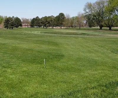 Open fairway with scattered mature trees on a sunny spring day at Poco Creek Golf Course in Aurora, Nebraska