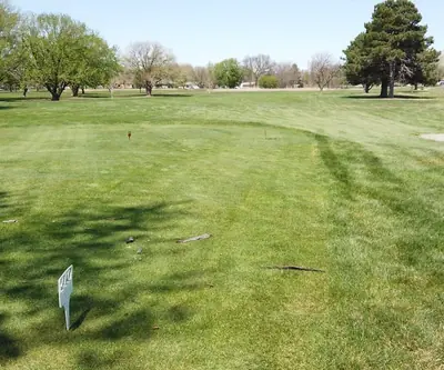 Tee box with small orange markers facing an open fairway dotted with trees at Poco Creek Golf Course in Aurora, Nebraska