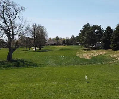 Tee view across a rolling fairway with bare trees and pines at Poco Creek Golf Course in Aurora, Nebraska