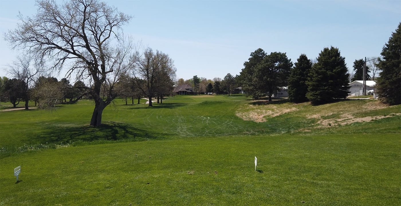 Tee view across a rolling fairway with bare trees and pines at Poco Creek Golf Course in Aurora, Nebraska