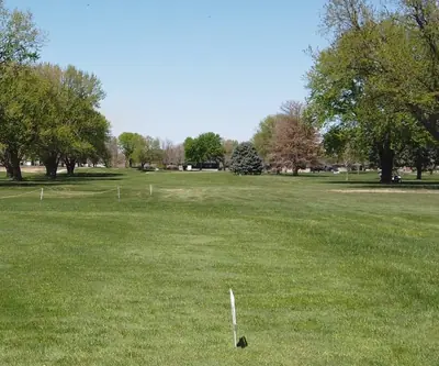 Roped-off fairway lined with mature trees under a clear sky at Poco Creek Golf Course in Aurora, Nebraska