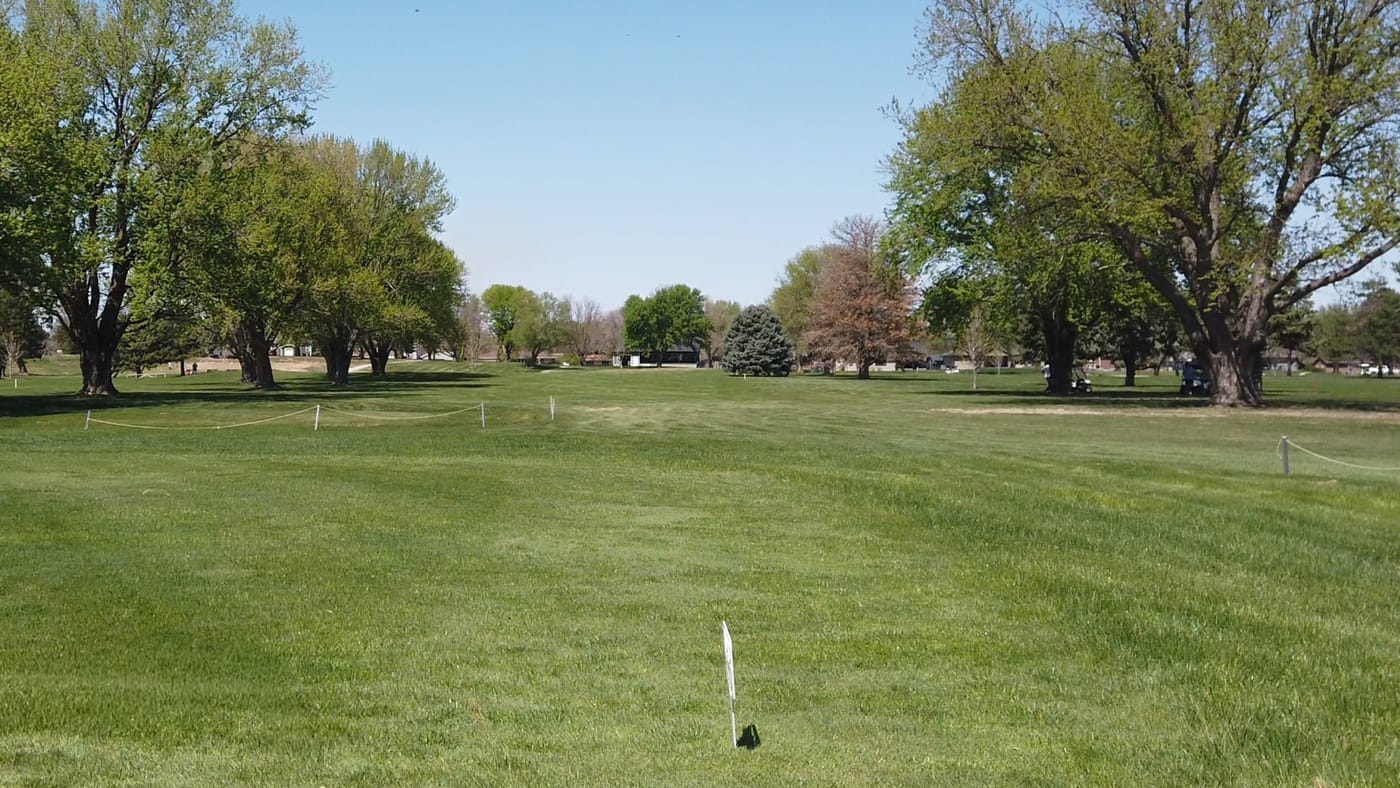 Roped-off fairway lined with mature trees under a clear sky at Poco Creek Golf Course in Aurora, Nebraska