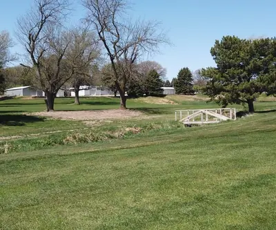 Small white footbridge crossing a grassy creek bed between fairways at Poco Creek Golf Course in Aurora, Nebraska
