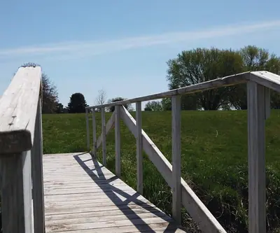 Weathered wooden footbridge leading onto a grassy slope at Poco Creek Golf Course in Aurora, Nebraska