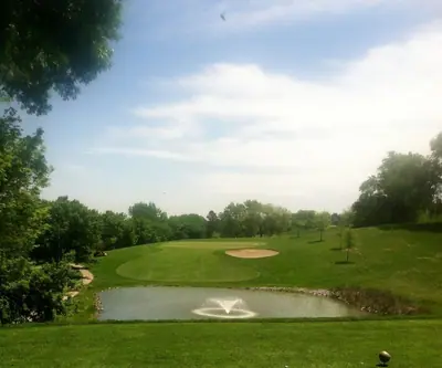 Tee view over a pond with a fountain to a green and bunker at Indian Trails Country Club in Beemer, Nebraska
