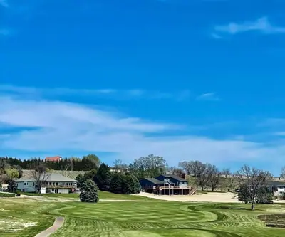 Striped fairway leading toward hillside homes under a bright blue sky at Cross Creek Golf Links in Cambridge, Nebraska