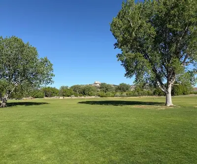Cottonwood trees frame a wide fairway below a rocky butte at Legend Buttes Golf Course in Crawford, Nebraska