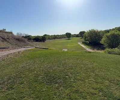 Elevated tee view down a fairway bordered by trees and cart paths at Legend Buttes Golf Course in Crawford, Nebraska