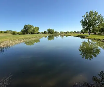 Calm pond reflecting leafy trees between two fairways at Legend Buttes Golf Course in Crawford, Nebraska