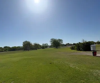 Tee area looking down a wide, open fairway toward scattered trees at Legend Buttes Golf Course in Crawford, Nebraska