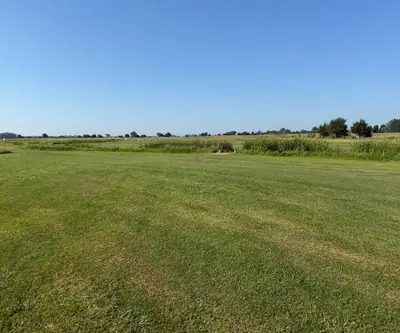 Wide mowed fairway leading to a band of tall native grass at Dannebrog Country Club in Dannebrog, Nebraska