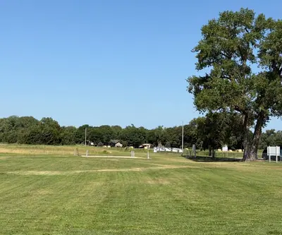 Open mowed grass and a tall shade tree near the parking area at Dannebrog Country Club in Dannebrog, Nebraska