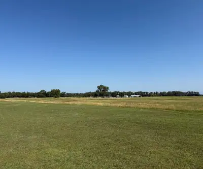 Wide open fairway bordered by tall prairie grass and a distant tree line at Dannebrog Country Club in Dannebrog, Nebraska
