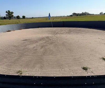 Raked circular sand green with a blue flag, ringed by metal edging at Dannebrog Country Club in Dannebrog, Nebraska