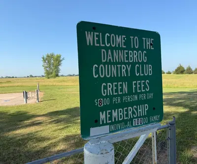 Welcome sign listing green fees and membership rates at Dannebrog Country Club in Dannebrog, Nebraska