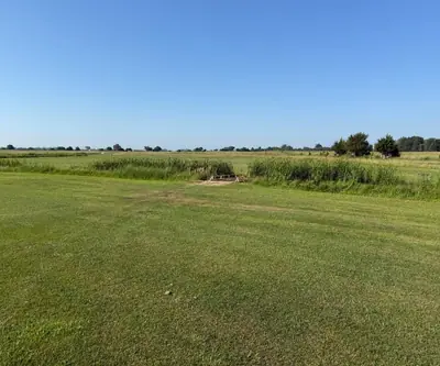 Small wooden footbridge crossing a grassy ditch between fairways at Dannebrog Country Club in Dannebrog, Nebraska