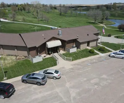 Clubhouse with a striped awning and American flag beside the parking lot at Falls City Golf Course in Falls City, Nebraska