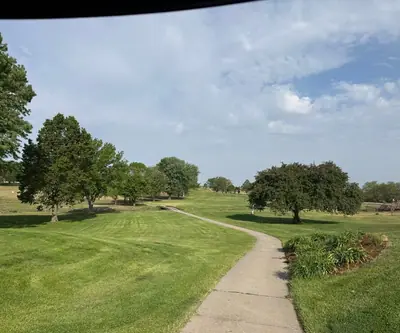 Cart path winding through mowed fairways and shade trees at Hidden Hills Country Club in Geneva, Nebraska