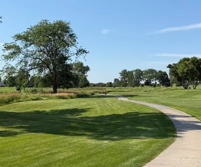 Curving cart path past a big shade tree and tall grasses along a fairway at Southern Hills Golf Club in Hastings, Nebraska