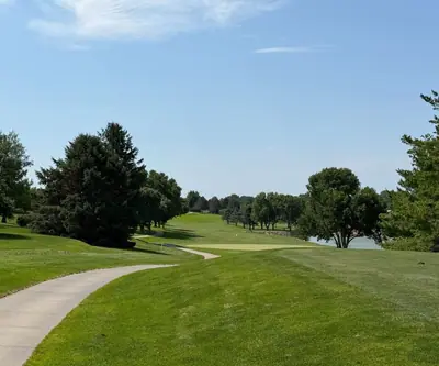 Cart path along a tree-lined fairway leading to a green beside a pond at Southern Hills Golf Club in Hastings, Nebraska