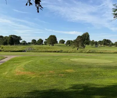 Green beside a cart path with a footbridge and tree-dotted fairways beyond at Southern Hills Golf Club in Hastings, Nebraska