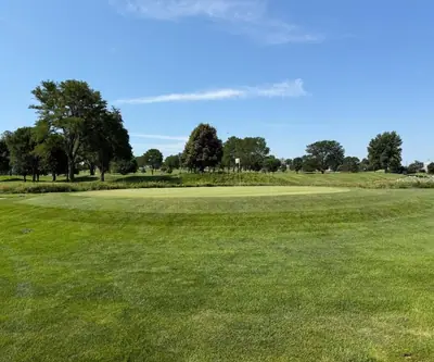 Putting green with a white flag framed by mature shade trees at Southern Hills Golf Club in Hastings, Nebraska