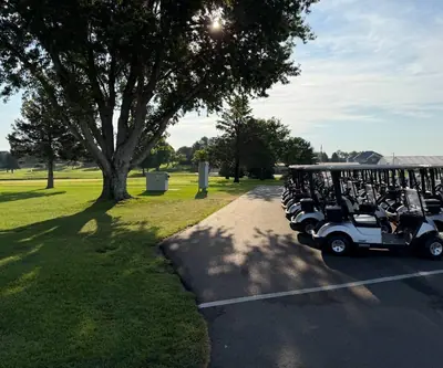 Row of golf carts parked beside a large shade tree at Southern Hills Golf Club in Hastings, Nebraska