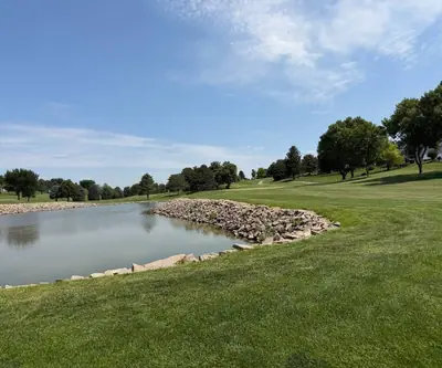 Rock-lined pond beside a rolling fairway with homes beyond at Southern Hills Golf Club in Hastings, Nebraska