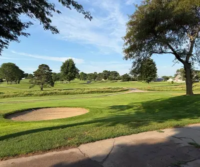 Round bunker beside a curving cart path and mature shade trees at Southern Hills Golf Club in Hastings, Nebraska