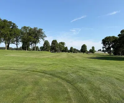 Wide mowed fairway lined with mature trees under a blue sky at Southern Hills Golf Club in Hastings, Nebraska