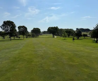 Wide mowed fairway lined with scattered shade trees on a sunny day at Southern Hills Golf Club in Hastings, Nebraska