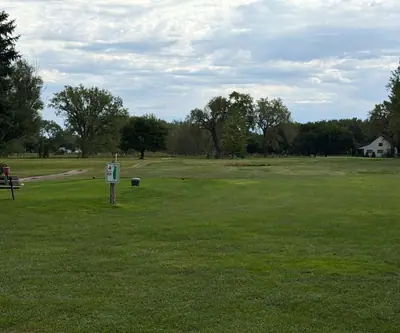 Hole 4 tee sign, bench and ball washer facing an open fairway at Loup City Golf Club in Loup City, Nebraska