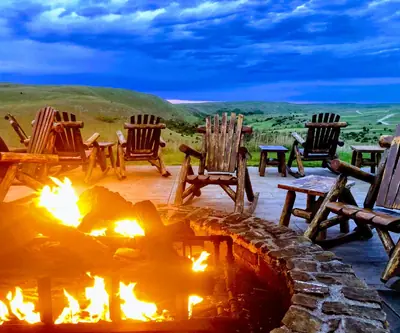 Fire pit and log rocking chairs overlooking the Sandhills at dusk at Dismal River Club in Mullen, Nebraska