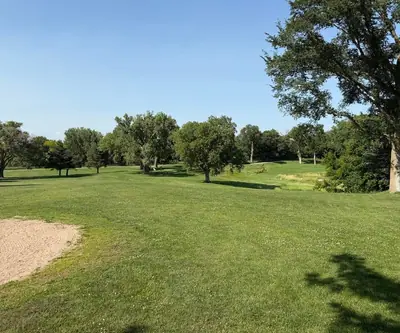 Tree-lined fairway with a sand bunker in the foreground at Shell Creek Valley Golf Course in Newman Grove, Nebraska